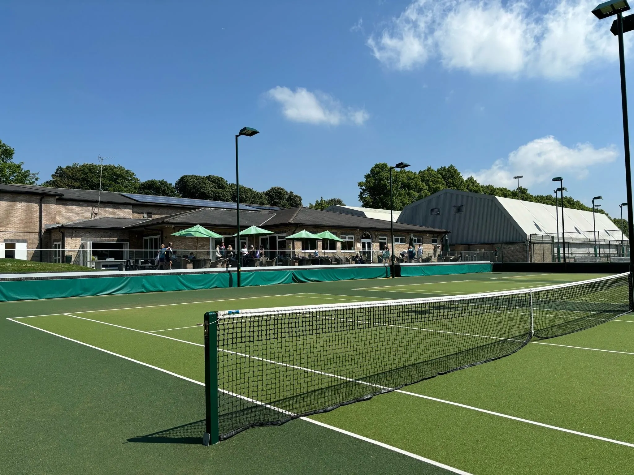 A view of the clubhouse from a tennis court on a clear, sunny day.